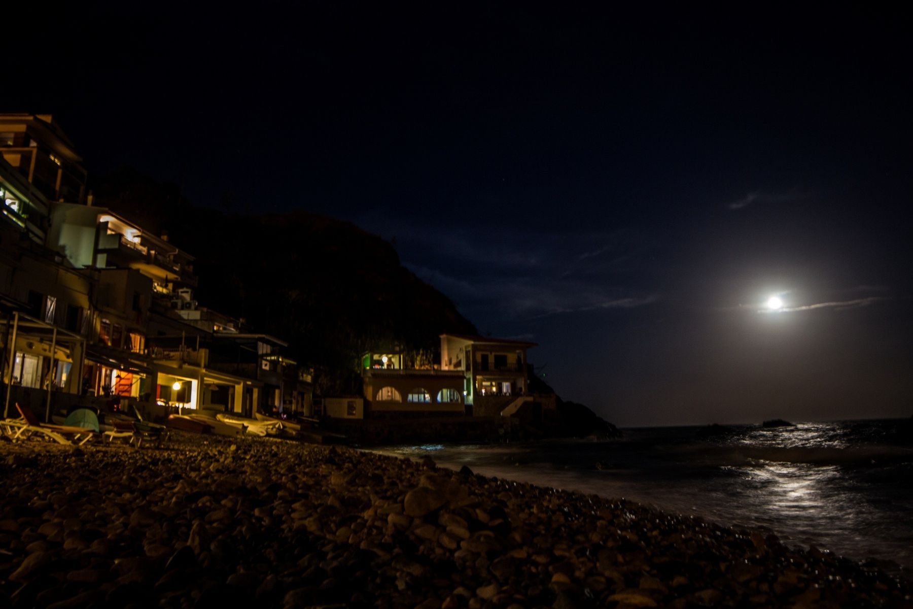 Pueblo costero iluminado de noche bajo la luna